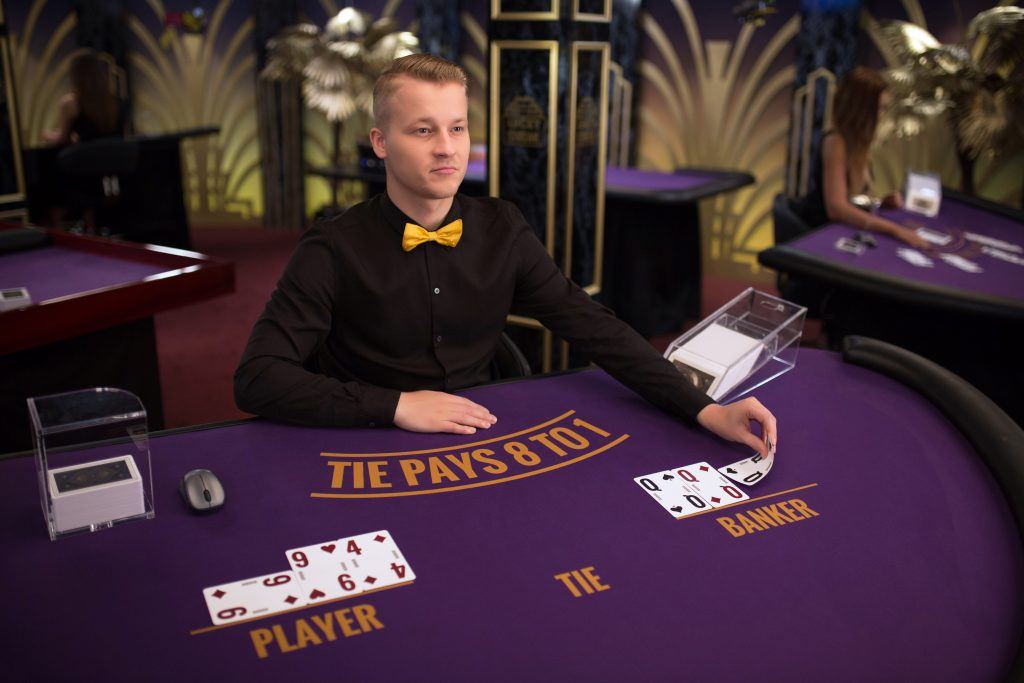 Dealer live casino membagikan kartu di meja baccarat